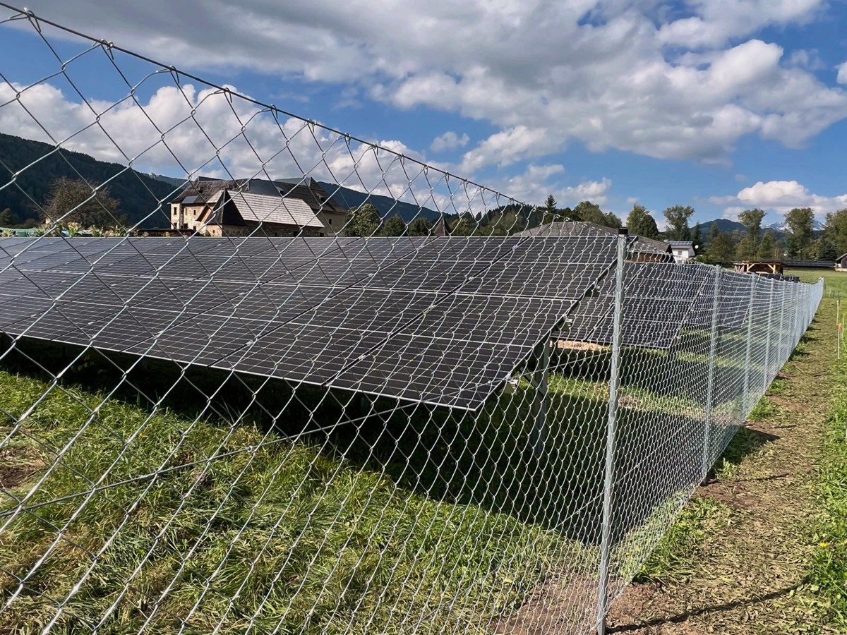 Maschendrahtzaun vor Photovoltaik-Modulen im Alpenvorland
